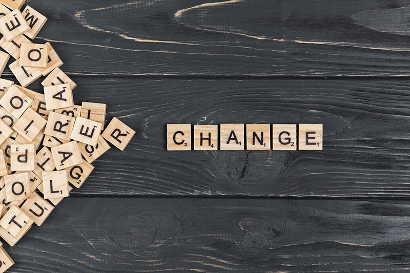 Blocs de lettres en bois formant le mot CHANGE sur une table en bois noir.