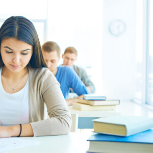 Étudiante concentrée en train d'écrire, symbolisant l'importance de la concentration et de la gestion du stress pour réussir ses études.
