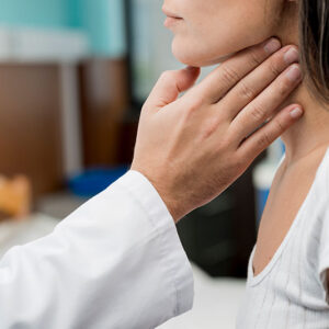 Examen de la thyroïde par un professionnel de santé, représentant les maladies auto-immunes comme la thyroïdite de Hashimoto.