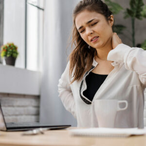 Jeune femme tenant son cou et son dos en raison de douleurs, illustrant les troubles musculo-squelettiques liés au travail sur ordinateur.