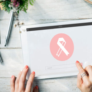 Main utilisant une tablette avec un ruban rose affiché à l'écran, symbole de la sensibilisation au cancer du sein.