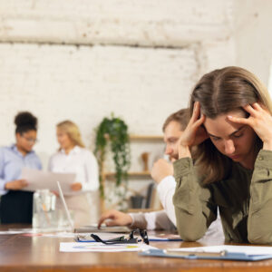 Femme au bureau tenant sa tête avec une expression de stress, symbolisant les défis du stress au travail.