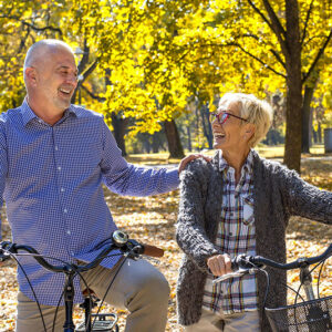 Couple de séniors faisant du vélo dans un parc, illustrant la santé et la vitalité grâce à un mode de vie sain.